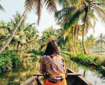 Woman on a boat ride through the lush Kerala backwaters surrounded by palm trees