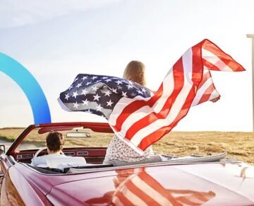 Woman holding an American flag in a convertible during a road trip in the USA