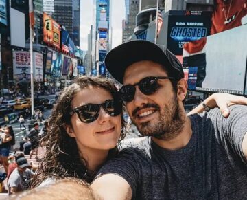 Couple taking a selfie at Times Square in New York City with billboards in the background